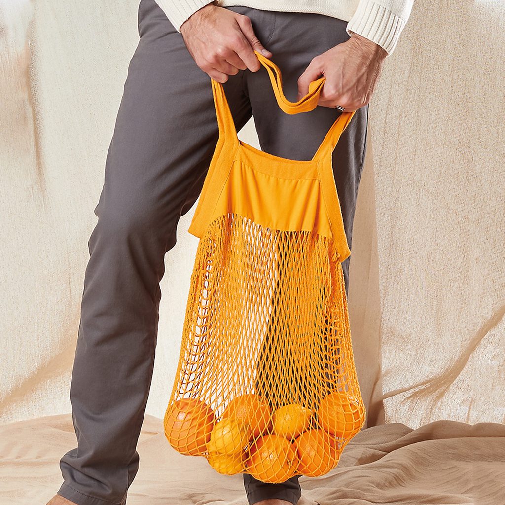 Man Holding Amber Organic Mesh Shopper Filled With Mixed Fruit