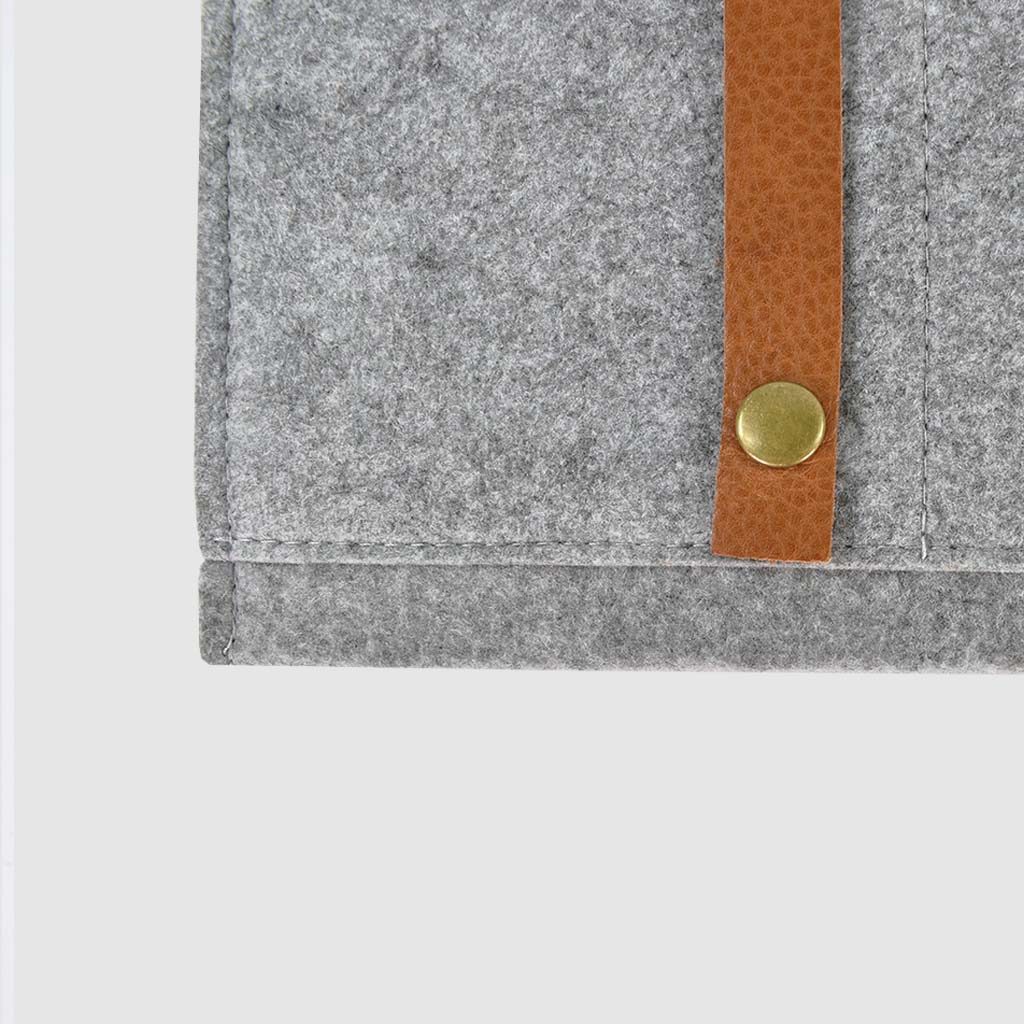 metal rivet detail on brown leather strap on felt folder