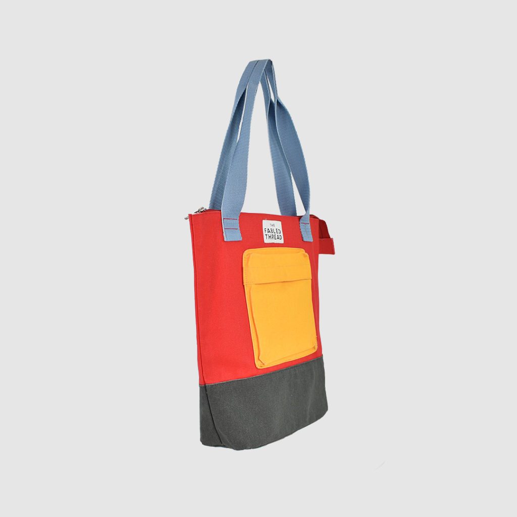 Custom heavyweight canvas bag side view of red bag with yellow pocket and grey base and blue handles