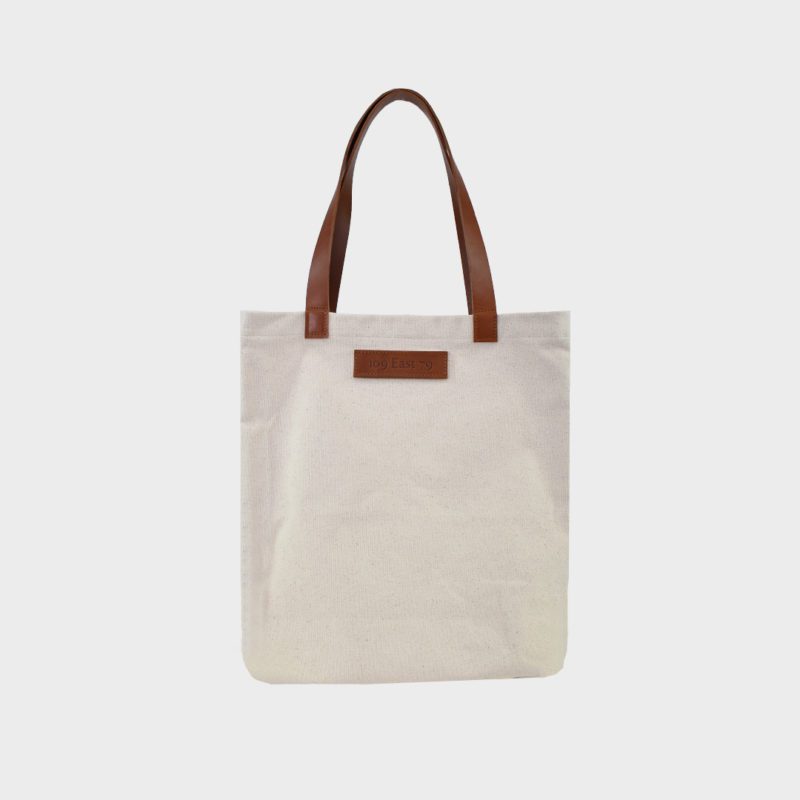 natural canvas tote bag with tan colour PU leather handles and embossed brand badge