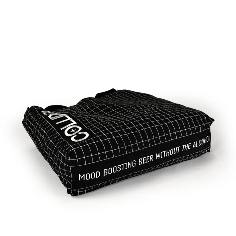 black tote bag with gusset lying flat on the ground showing the white print on the base of the bag