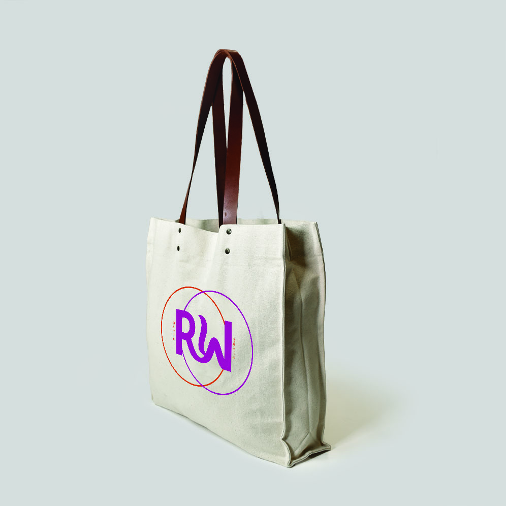 side view of a natural bag with leather handles and metal rivets. Print is orange and pink